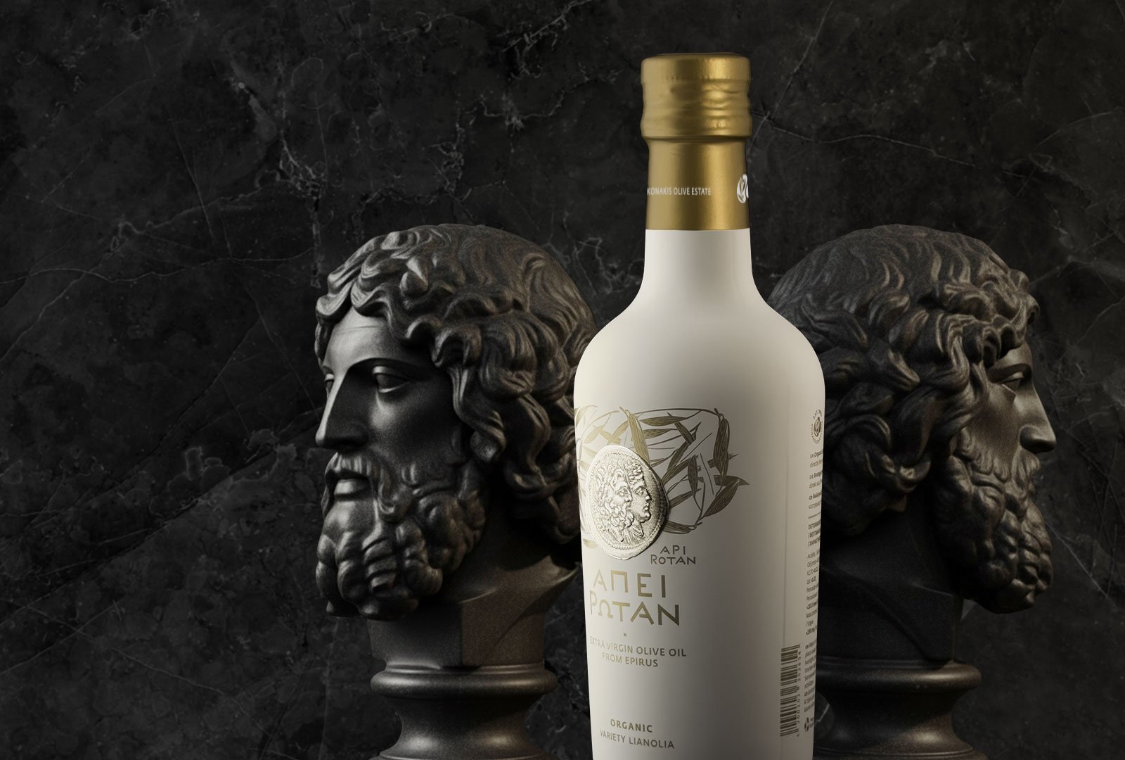 Api Rotan organic extra virgin olive oil bottle with minimalist white packaging and ancient coin label, set against a dark marble background with classical Greek sculptural busts.