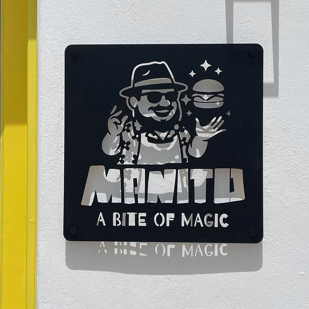 Εξωτερική πινακίδα ΜΑΝΙΤΟ με το λογότυπο A BITE OF MAGIC σε μαύρο και κίτρινο.